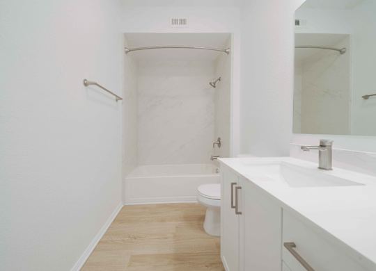 A white bathroom with a toilet, sink, and bathtub.