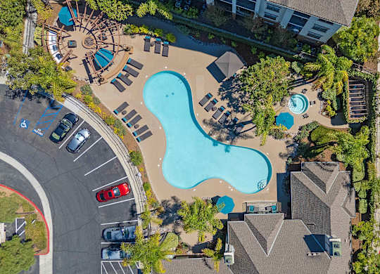 An aerial view of a swimming pool surrounded by trees and buildings.