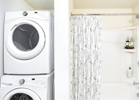 A white washing machine and dryer stacked on top of each other in a laundry room.