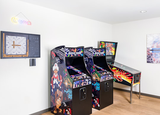 Two arcade style game machines with a table and chairs in between.