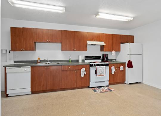 a kitchen with white appliances and wooden cabinets and a white stove and refrigerator at The Groves at Wimauma Apartments , Wimauma, Florida