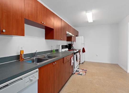a kitchen with wood cabinets and a sink and a stove and a refrigerator at The Groves at Wimauma Apartments , Wimauma
