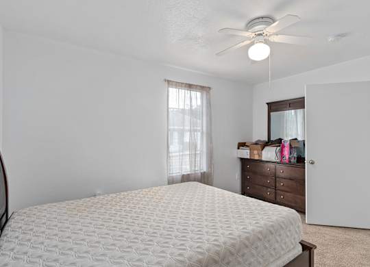 an empty bedroom with a bed and a ceiling fan at The Groves at Wimauma Apartments , Wimauma, FL, 33598