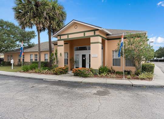 the front of a building with flags and palm trees at The Groves at Wimauma Apartments , Wimauma, FL, 33598