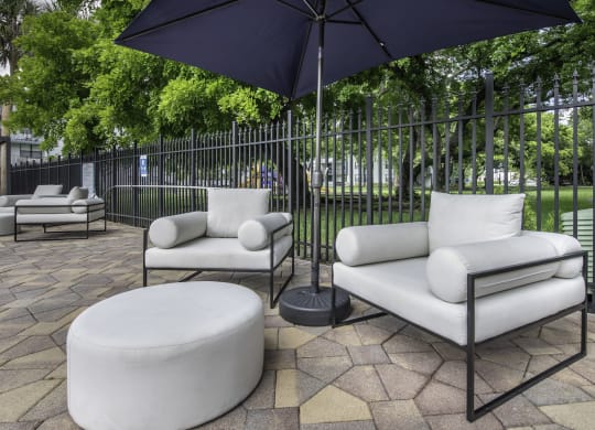 a patio with two white couches and two black umbrellas  at Club at Emerald Waters, Florida