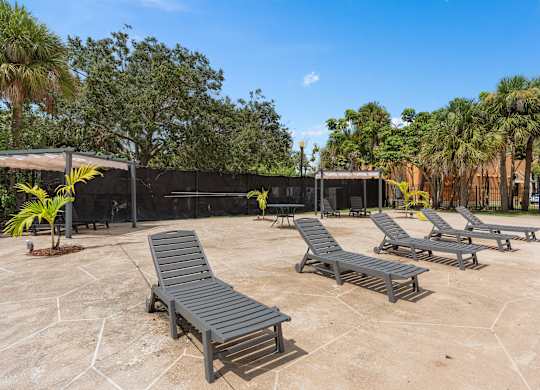 a group of lounge chairs on a patio with trees at Cypress Grove, Lauderhill