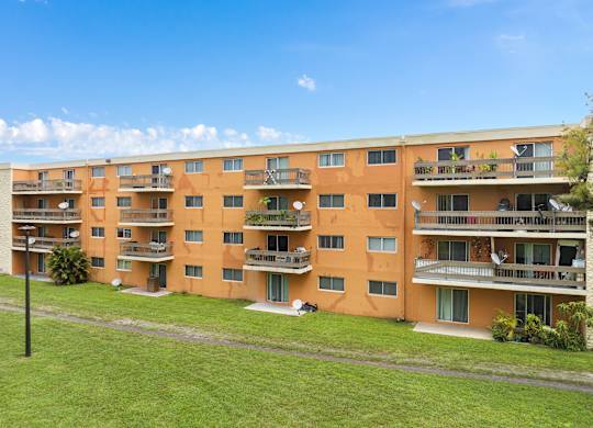 a large apartment building with balconies and a green lawn at Cypress Grove, Lauderhill, 33313