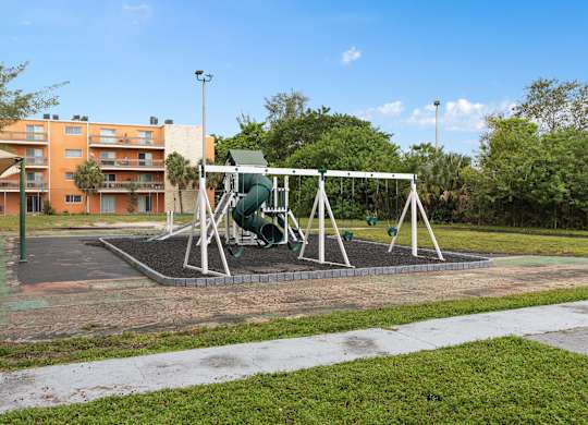 a swing set in a park in front of a building at Cypress Grove, Lauderhill
