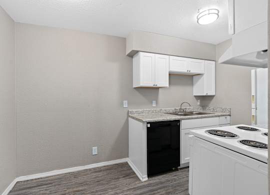 an empty kitchen with white cabinets and a black and white stove at Emerald Greens, Norman, OK
