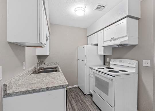 a kitchen with white appliances and white cabinets and a sink at Emerald Greens, Norman, OK 73072