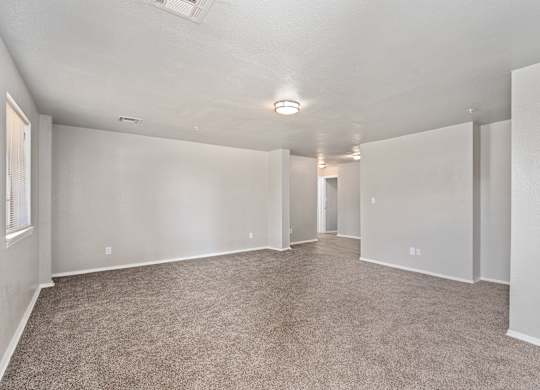 an empty living room with carpet and white walls at Emerald Greens, Norman, 73072
