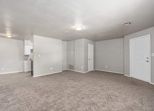 an empty living room with carpet and a white kitchen at Emerald Greens, Oklahoma