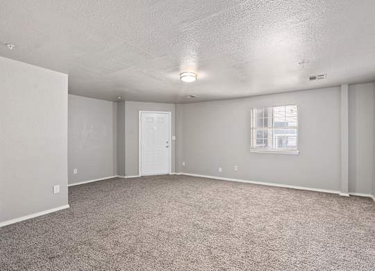 an empty living room with carpet and a white door at Emerald Greens, Norman, OK 73072