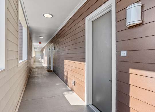 a long hallway with wood paneled walls and a silver door at Lake Lofts at Deerwood, Jacksonville