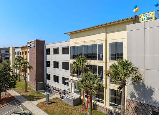 a large building with palm trees in front of it at Lake Lofts at Deerwood, Florida, 32216