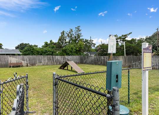 a park with a chain link fence and a seesaw in the grass at Oak Reserve at Winter Park, Winter Park, FL