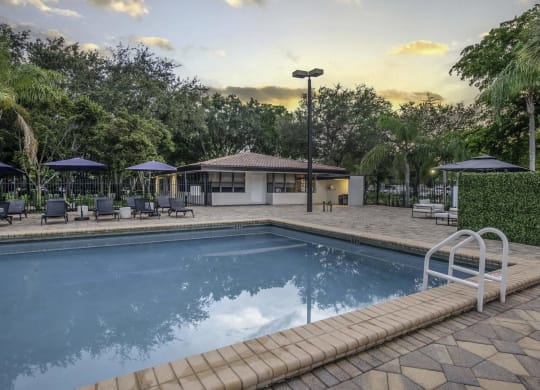 a resort style pool with lounge chairs and umbrellas  at Club at Emerald Waters, Hollywood, FL
