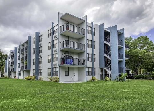 a grey apartment building with a green lawn in front of it  at Club at Emerald Waters, Florida