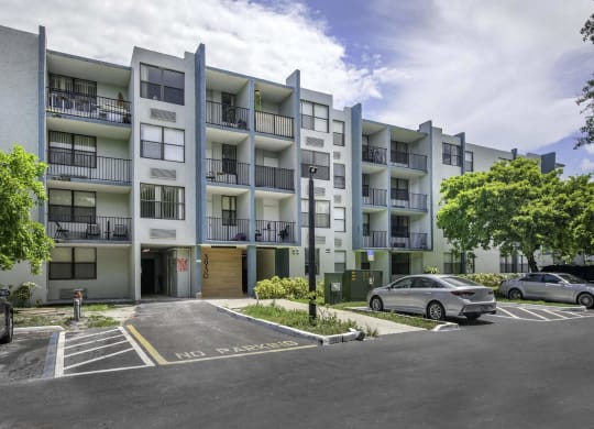 an image of an apartment building with a parking lot in front of it  at Club at Emerald Waters, Hollywood, FL