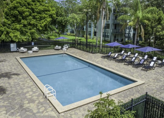 a swimming pool with lounge chairs and umbrellas in front of an apartment building  at Club at Emerald Waters, Hollywood, FL