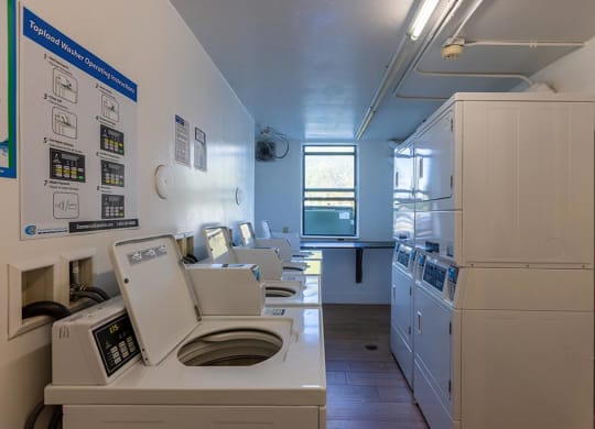 a laundry room with a row of washers and dryers  at Club at Emerald Waters, Hollywood, FL, 33021