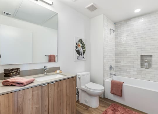 Beautiful bathroom with a soaking tub and pink towel layed over the side of tub along with a pink floor mat.