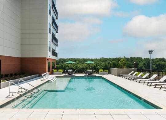 Sparkling swimming pool with sun tanning ledge, lounge chairs and two covered bistro tables  at Chapter at the Streets of St Charles, Missouri, 63303