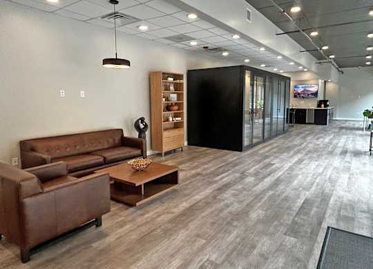 A modern office space with a brown leather sofa and a wooden coffee table.