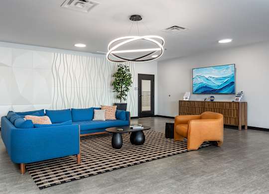 A modern living room with a blue sofa, a wooden side table, and a large screen TV.