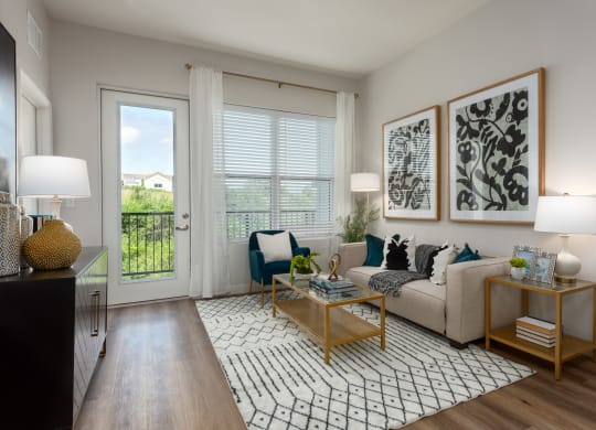 Modern living room with a couch coffee table, large window a door leading to a balcony  at Chapter at the Streets of St Charles, Saint Charles, MO