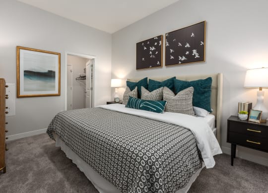 Modern bedroom with large bed, night stand, dresser and door leading to walk-in closet  at Chapter at the Streets of St Charles, Saint Charles, MO, 63303