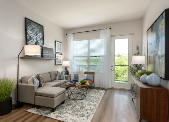 Modern living room with a couch coffee table, large window a door leading to a balcony  at Chapter at the Streets of St Charles, Saint Charles, 63303