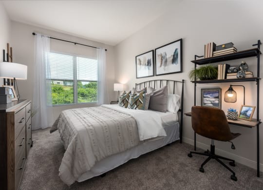Modern bedroom with large window, bed, dresser and small work station  at Chapter at the Streets of St Charles, Saint Charles, MO, 63303