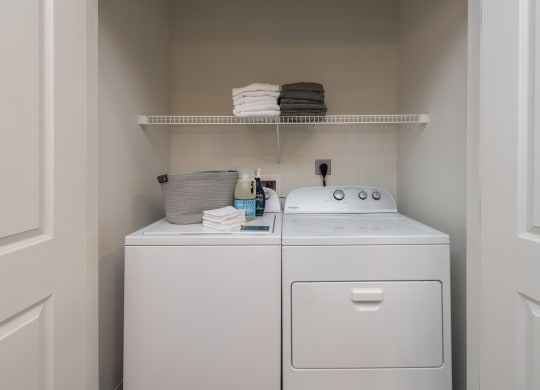 Full-size washer and dryer in unit with wire shelf above  at Chapter at the Streets of St Charles, Missouri
