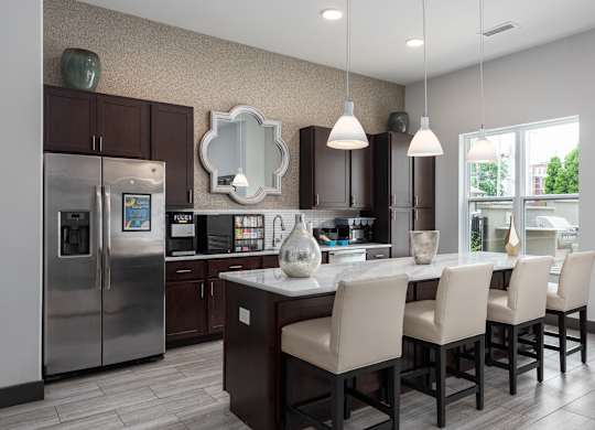 A modern kitchen with a large island and chairs.