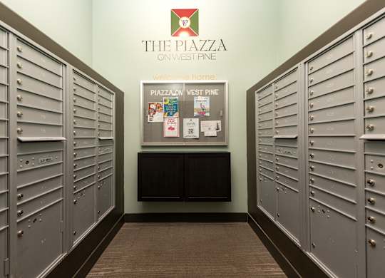 A hallway with lockers and a sign that says The Piazza on West Pine.