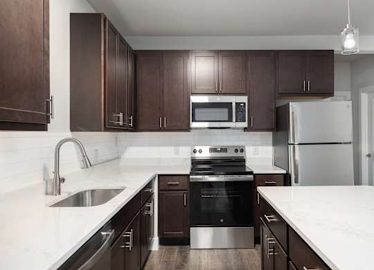 A modern kitchen with dark brown cabinets and stainless steel appliances.