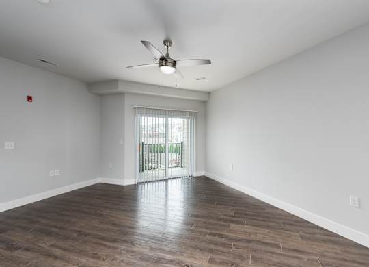 A room with a ceiling fan and sliding glass doors.