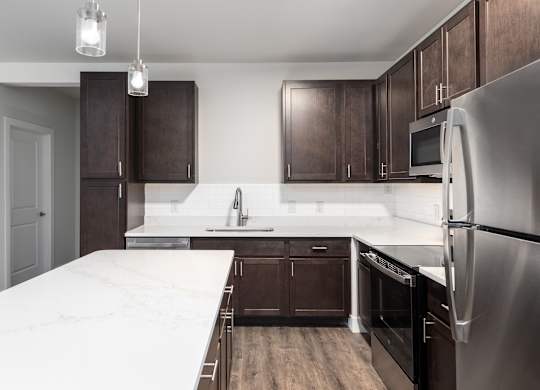 A kitchen with dark brown cabinets and a stainless steel refrigerator.