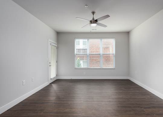 A room with a ceiling fan and a window with blinds.