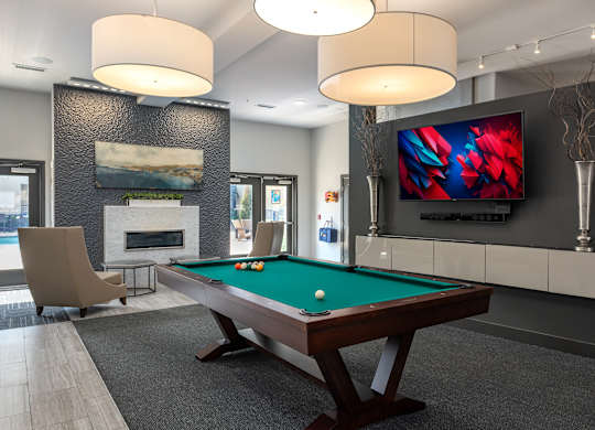 A room with a pool table and a television mounted on the wall.