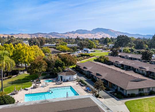 Aerial view of a pool with mountains in the background at The Grove at Walnut Creek Apartments in Walnut Creek, CA.