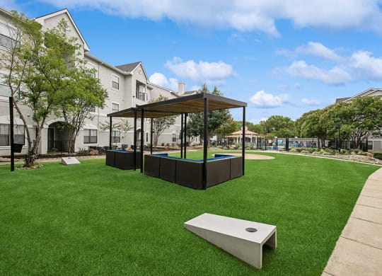 Outdoor Corn Hole Area and Lounge Furniture at Hidden Creek Apartments located in Lewisville, TX.