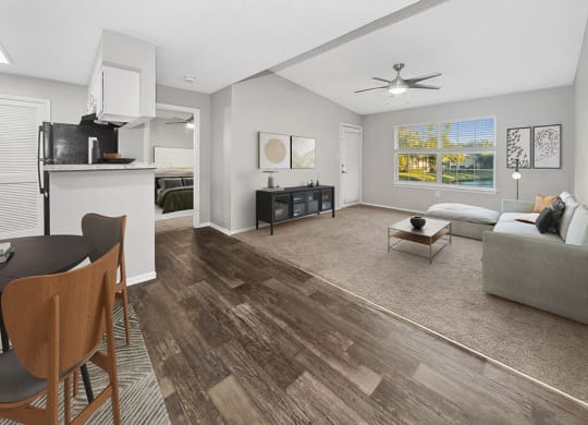 Model Dining Room and Kitchen Area with Wood-Style Flooring and View of Living Room at Walden Lake Apartments in Plant City, FL.