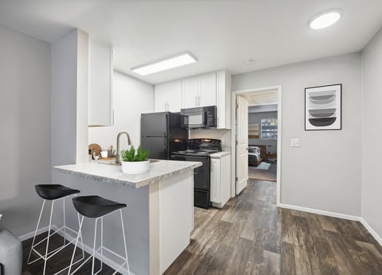 Model Kitchen with White Cabinets and Wood-Style Flooring at Country Club Verandas Apartments located in Mesa, AZ.