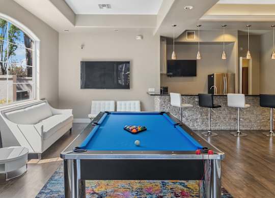 A pool table is in the middle of a room with a couch and a TV.