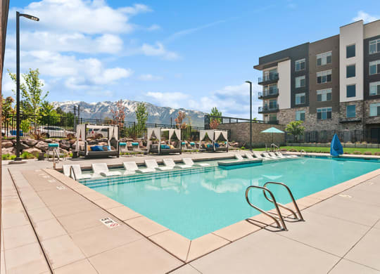 Community Swimming Pool with Pool Furniture  at Seven Skies Apartments located in Sandy, UT.