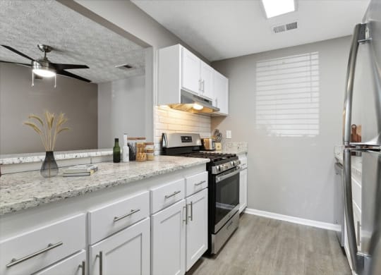 Model Kitchen with White Cabinets and Wood-Style Flooring at Dunwoody Village Apartments in Atlanta, GA.