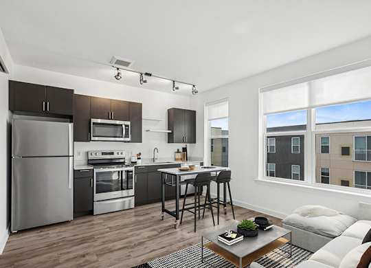 Model Kitchen with Dark Wood Cabinets and Wood-Style Flooring at Stella Apartments located in New Carrollton, MD.