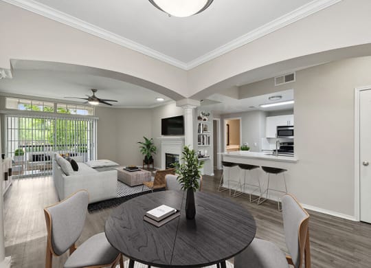 Model Dining Room with Wood-Style Flooring and View of Living Room/Kitchen Area at Allure North Dallas Apartments located in Dallas, TX.